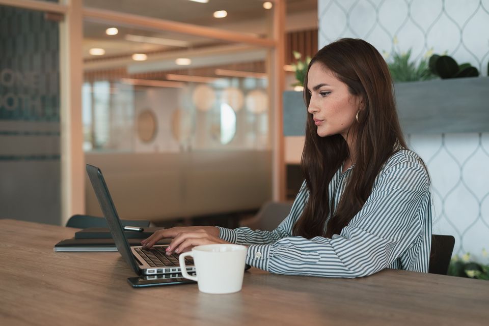 A woman working on a laptop in a naturally lit office