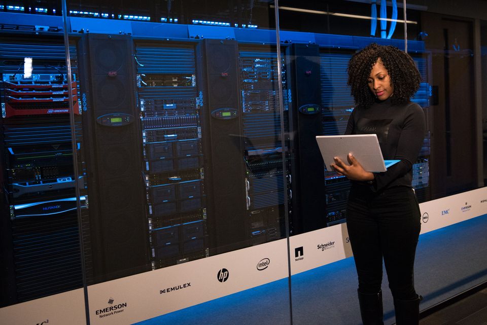 An engineer with a laptop checking server racks in a data centre