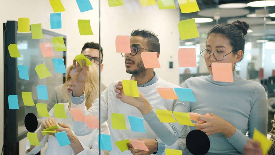 A team mapping ideas with sticky notes on a glass wall