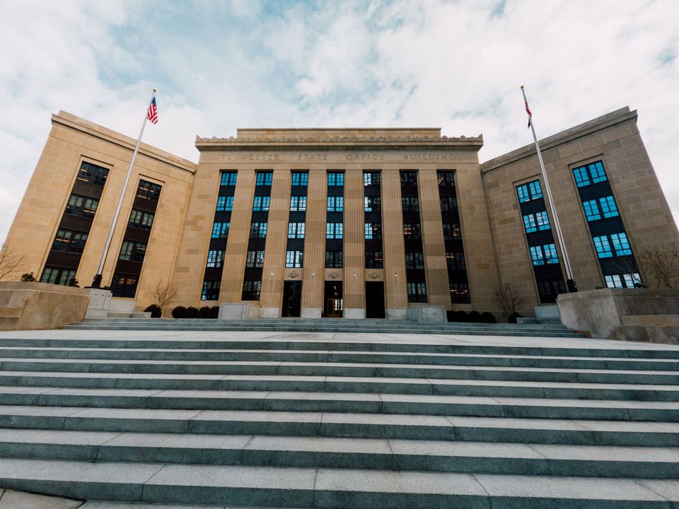 A government building with wide steps and flags under a clear sky
