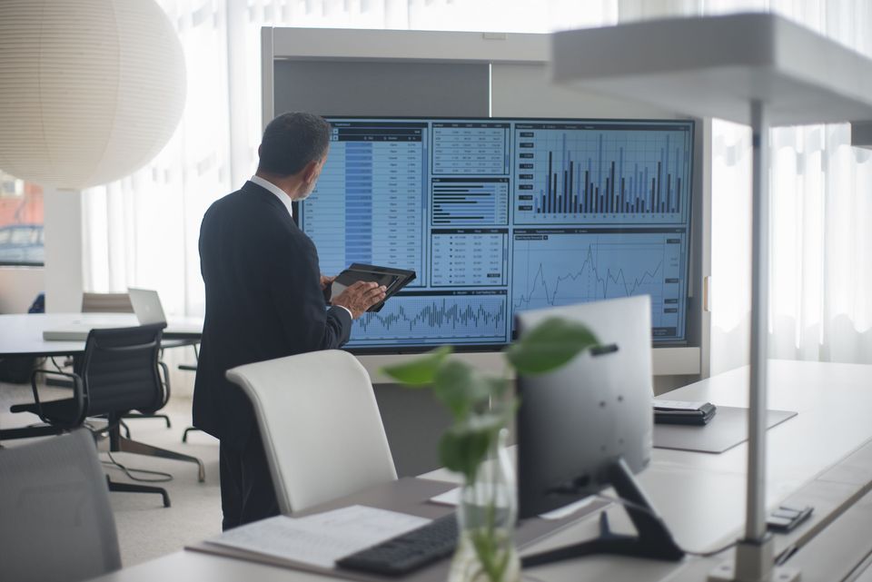An analyst reviewing data dashboards on large screens in a modern office